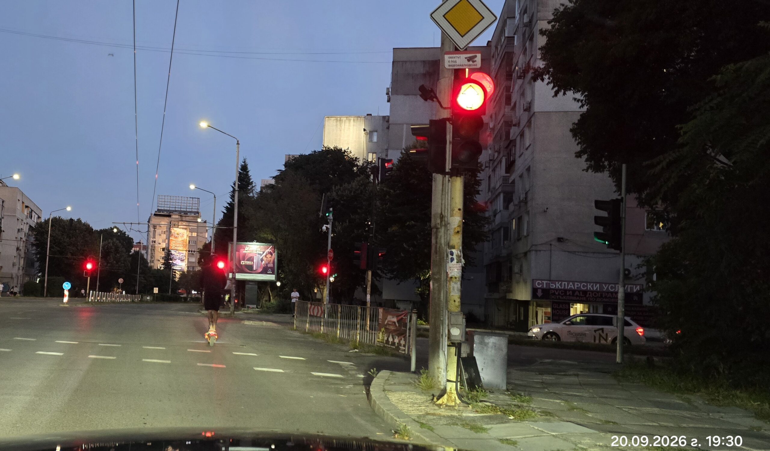 Водач на електрическа тротинетка се движи вечер в средата на платното на бул. Сливница във Варна пред светещ червен светофар.